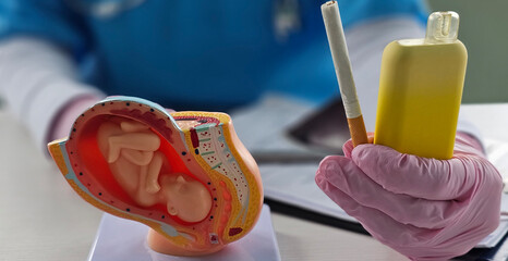 Gynecologist holds cigarette and vape with warning about dangers of smoking during pregnancy