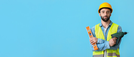 Construction worker with screw gun and builder level on blue background