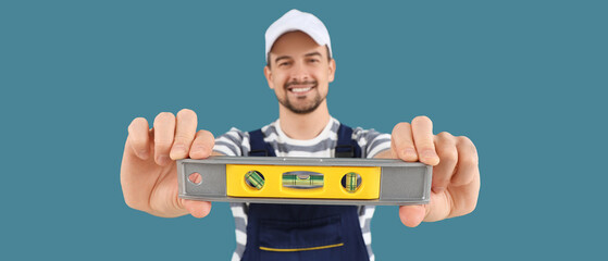 Male technician with level on blue background, closeup