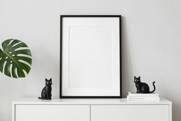 Black cat figurine sitting on top of a white dresser next to a framed poster.