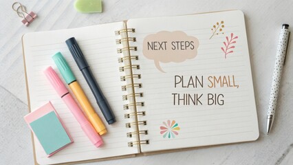 Inspirational notebook with colorful pens and motivational quote encouraging planning small and thinking big for success