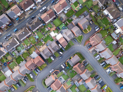 Overhead aerial view of suburban houses, streets and gardens, England