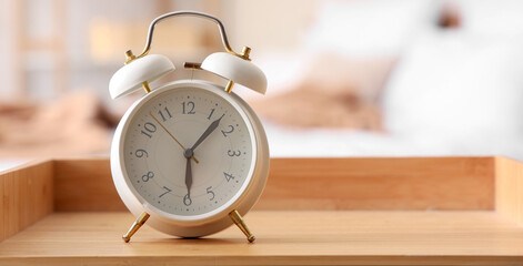 Alarm clock on wooden bedside table in bedroom, closeup