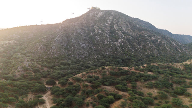 Aerial view of the Aravali mountains near Pushkar, Rajasthan, showing native trees like Ker, Babool, and Khejri, with the Savitri Mata Temple ropeway visible, capturing lush hills and cultural landmar