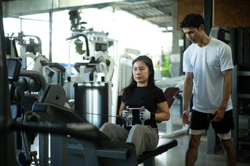 Fototapeta premium Trainer supervising woman during seated row workout