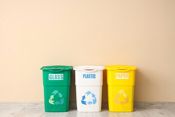 Empty trash bins for different types of garbage near beige wall. Recycling concept