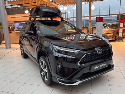 RIGA, LATVIA, DECEMBER 1, 2025: Three quarter front view of black Toyota RAV4 Hybrid in a modern showroom with warm lighting and reflective floor.
