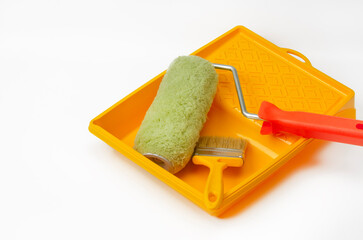On a white background are tools for home or apartment renovation - a roller and a paint brush