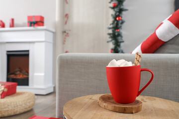 Cup of cocoa on table in hall decorated for Christmas, closeup
