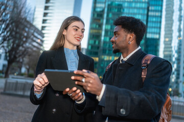Diverse business people collaborating on digital tablet outdoors