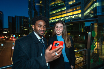 Diverse business colleagues networking, sharing smartphone content at night