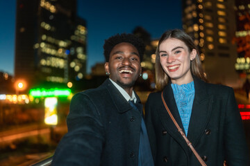 Diverse happy young couple taking selfie in city nightlife