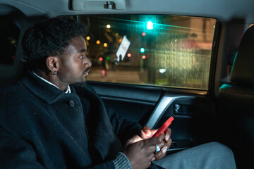 Afro american man traveling city at night using phone