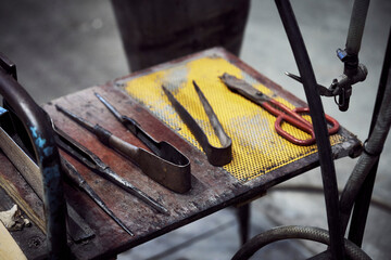 Glassblowing hand tools in a row on shelf in workshop
