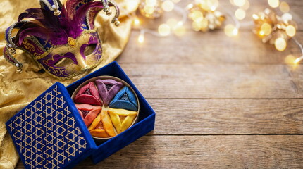 Purim holiday greeting card with carnival mask, blue gift box with gold Stars of David pattern and hamentashen cookies top view with space for text