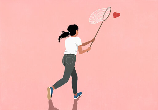 Woman chasing flying heart with butterfly net on pink background
