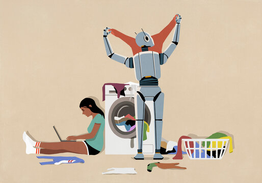 Humanoid robot folding laundry at dryer while teenage girl uses laptop
