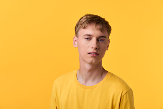 Bright studio shot of a young man in a yellow shirt against a vivid yellow backdrop, presenting a calm, casual mood ideal for lifestyle, fashion, or promotional campaigns in digital media.