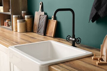 White ceramic sink and groceries on wooden counter near dark blue wall in kitchen