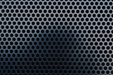 Closeup view of a dark, perforated metal surface with a regular pattern of small circular holes