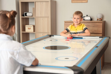 Obraz premium Little boy with girl playing air hockey at home