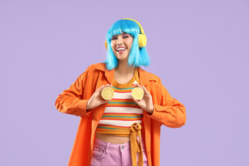 Fototapeta premium Beautiful young happy woman in blue wig and headphones with lemons halves on purple background