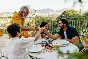 Fototapeta premium Family enjoying a barbecue meal on a terrace with a scenic view