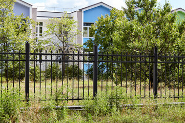 Fototapeta premium Metal fence in the city park. Decorative black iron guardrail for protection, close up