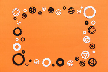 Frame made of different paper gears on orange background