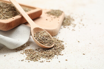 Wooden board, spoon and tray with dried anise seeds on light background