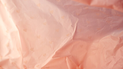 Pink plastic background with soft light on the left and deep tone on right. Wrinkled plastic paper texture background. Close-up crumpled texture, minimal, art, reflection for wallpaper, resource.