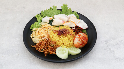 Indonesian traditional food, nasi kuning yellow turmeric rice served with vegetables, spicy eggs, noodles and tempeh