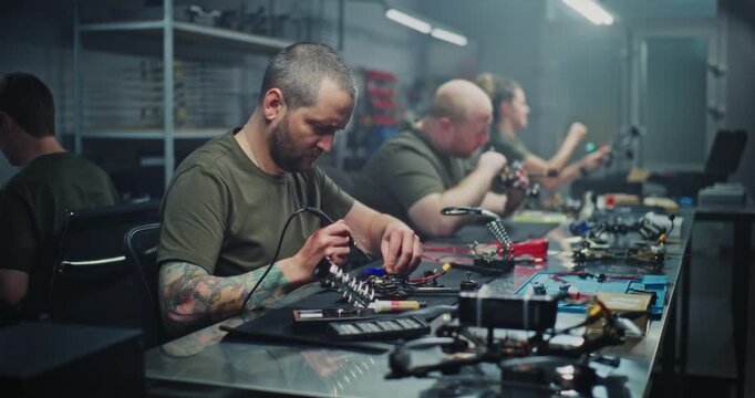 Diverse Specialists, Including Men and Women, Perform Various Tasks Like Soldering and Computer Design in High Tech Workshop. Concept of Specialized Roles and Gender Diversity in Drone Development.