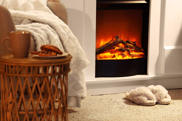 Fluffy slippers on soft carpet near fireplace in living room