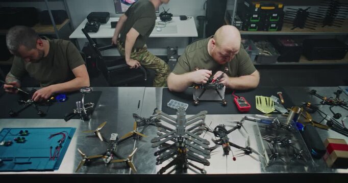 Engineers Meticulously Assembling, Soldering, and Preparing FPV Drone Units and Organizing Components For Quality Control. Concept of Detailed, Hands on Work in Electronics Production. Top View.