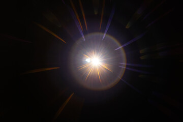 Lens Flare. Light over black background. Easy to add overlay or screen filter over photos. Abstract sun burst with digital lens flare background. Gleams rounded and hexagonal shapes, rainbow halo.