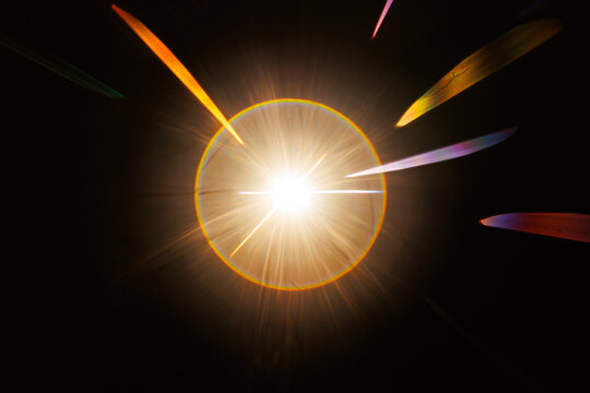 Lens Flare. Light over black background. Easy to add overlay or screen filter over photos. Abstract sun burst with digital lens flare background. Gleams rounded and hexagonal shapes, rainbow halo.