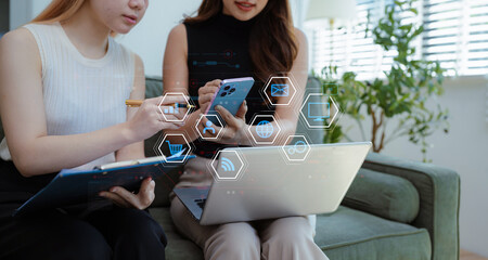 Business documents on office table with smart phone, tablet and laptop computer and graph with social network diagram and two colleagues discussing data in office.