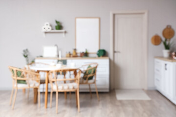 Blurred view of stylish kitchen with dining table, counters and white door
