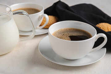 Cups of hot coffee with sweet cookies and jug of fresh milk on white background