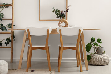 Vase with eucalyptus branches and clean dishes on dining table in light room