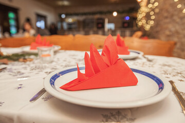 Elegant red napkin fold on white plate with bokeh lights at Christmas table
