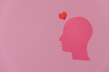 A pink silhouette of a human head with a red heart above it. The background is a solid pink color, creating a simple and clean design.