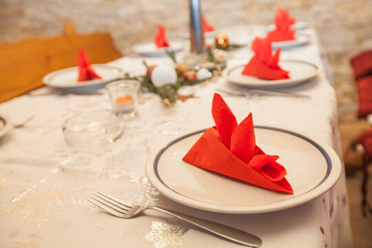 Elegant red napkin fold on white plate with bokeh lights at Christmas table - Powered by Adobe