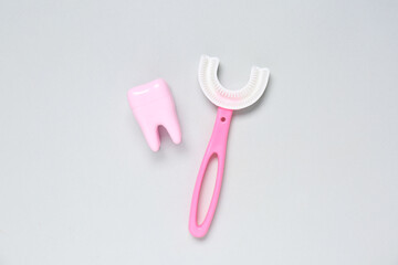 Tooth model with children's toothbrush on grey background