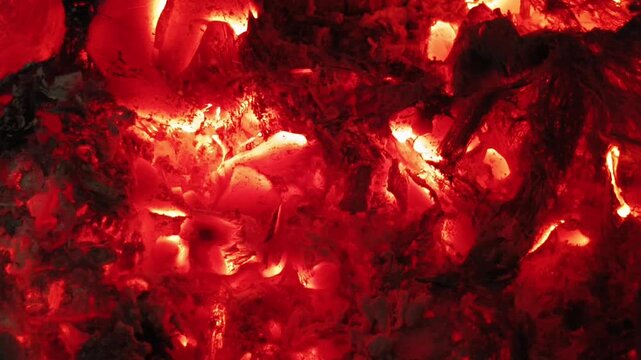 Closeup of red hot fiery smoldering dark charcoal, wood or coal burning heat glow abstract background texture for graphic design use. Fireplace, campfire, ignition or inferno concept.
