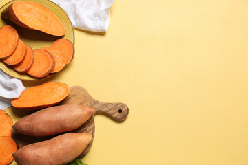 Plate and cutting board with fresh sweet potatoes on yellow background