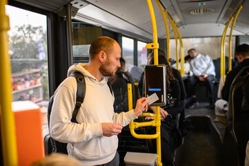 Man riding a bus and validating his ticket on public transport, commuting, urban daily routine, city lifestyle and transportation concept. © Mariia Andreeva