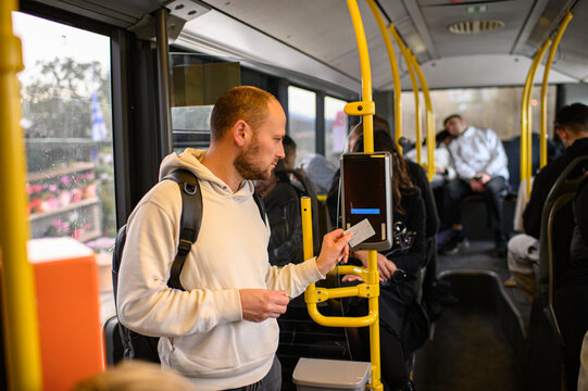 Man riding a bus and validating his ticket on public transport, commuting, urban daily routine, city lifestyle and transportation concept.