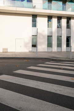 A minimalist building facade paired with a clean street view, offering a modern aesthetic complemented by the surrounding foliage and urban infrastructure.